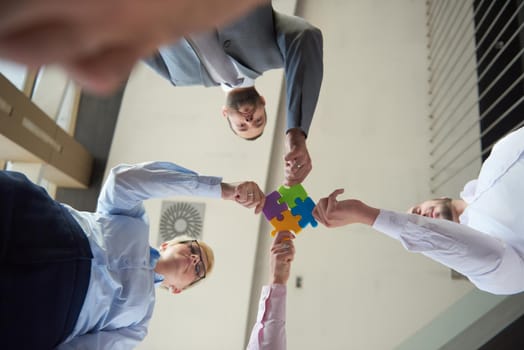 business people group assembling jigsaw puzzle and represent team support and help concept, top view perspective at modern bright office interior