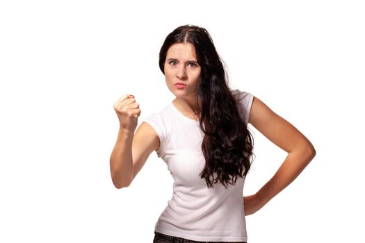 The portrait the young beautiful woman threatens with a fist is isolated on white