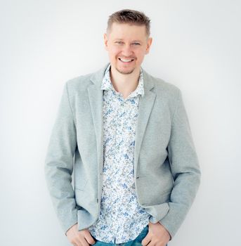 Smiling guy in floral shirt and jacket isolated on white background