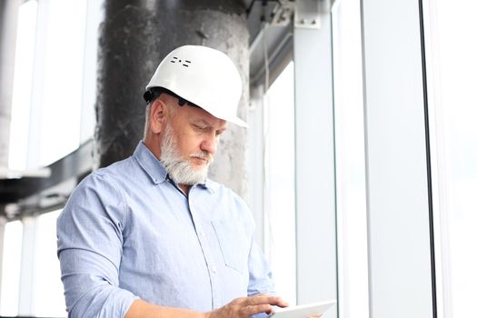 Mature architect wearing hardhat inspecting new building