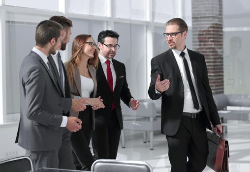 Group of five business partners in suits standing in large hall and discussing their reports for conference