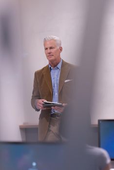 handsome mature teacher and students in computer lab classroom