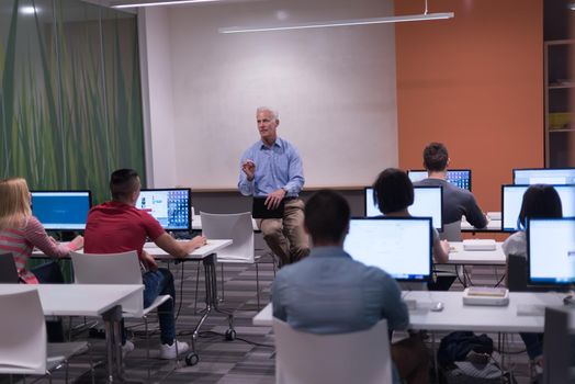 handsome mature teacher and students in computer lab classroom