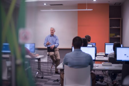 handsome mature teacher and students in computer lab classroom