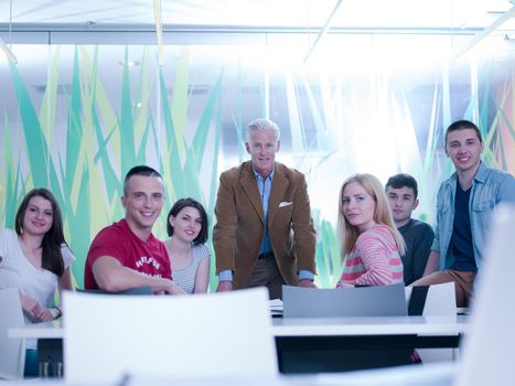 portrait of confident teacher in school classroom,  students group on class in background