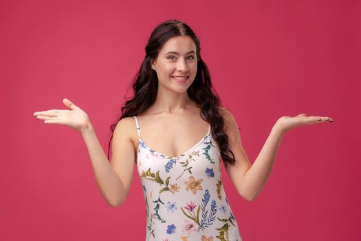 Beautiful, sweet, young girl spreads her arms on the pink background
