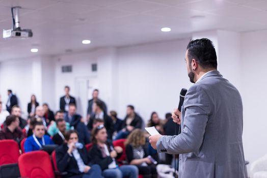 rear view of young successful businessman at business conference room with public giving presentations. Audience at the conference hall. Entrepreneurship club