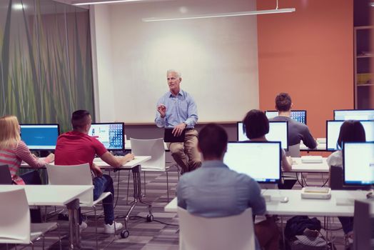 handsome mature teacher and students in computer lab classroom