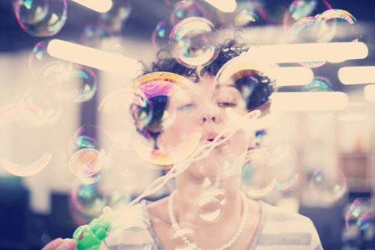 young female software developer having fun while making soap bubbles at modern startup office