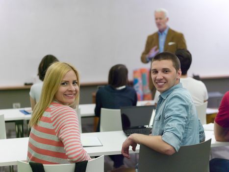 senior teacher with group of happy students in modern school classroom