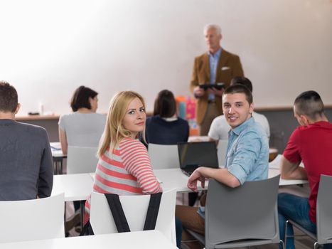 senior teacher with group of happy students in modern school classroom