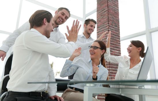employees give each other a high five sitting at the Desk. success concept