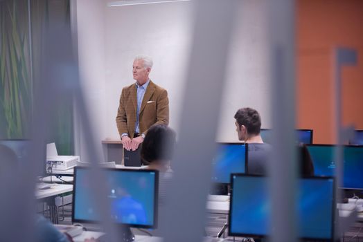 handsome mature teacher and students in computer lab classroom