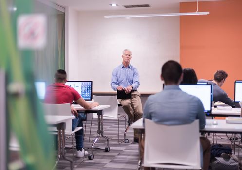 handsome mature teacher and students in computer lab classroom