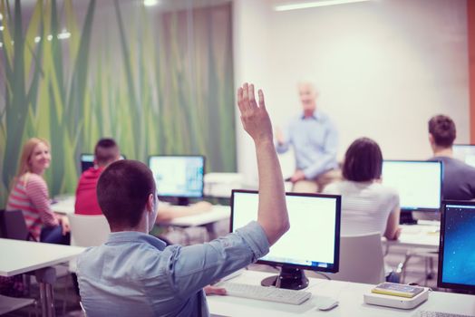 student answering a question in classroom, mature teacher and students in computer lab classroom