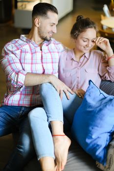 Young nice girl sitting with boyfriend at home and talking. Concept of happy couple, spending time together and relationship.