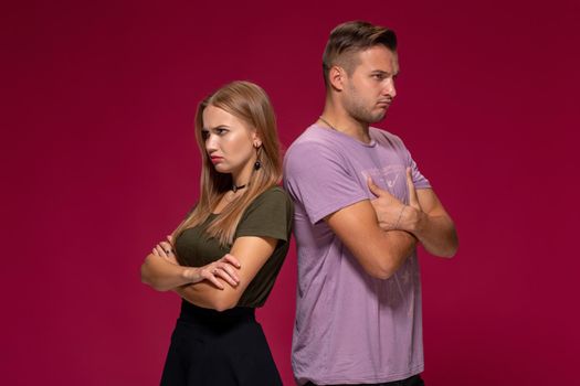 Studio portrait of a young couple in casual wear quarreled and taking a step towards reconciliation. The problem of relationships, quarrels, difficulties in communication