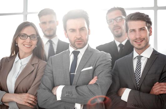 Team of successful happy businesspeople standing in office, businesswoman in front smiling.
