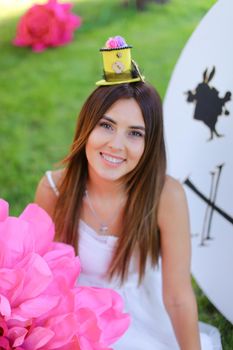 Young caucasian girl sitting at decorated place for children near big pink flower. Concept of beauty and festive decorations.