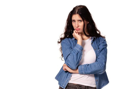 Beautiful and unhappy young woman with dark wavy hair looking into the camera with serious expression on her face. Isolated on white background.