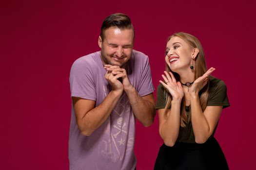 Girlfriend decided with her cute boyfriend to buy puppy. Maybe it will make their relationship stronger. Indoor studio shot on burgundy background.