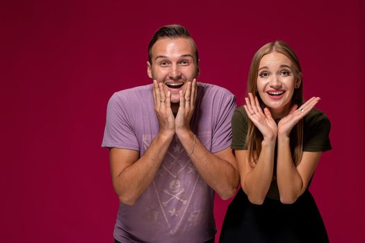 Girlfriend decided with her cute boyfriend to buy puppy. Maybe it will make their relationship stronger. Indoor studio shot on burgundy background.