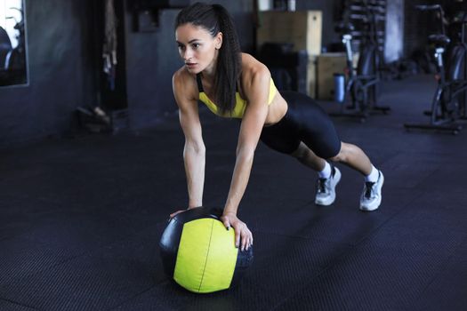 Muscular woman is working out with medicine ball in gym