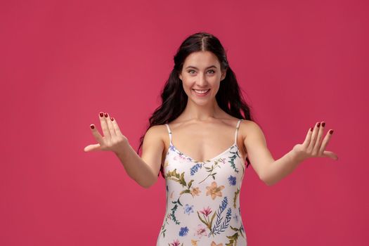 Close-up portrait of friendly pretty woman stretching her arms on pink background