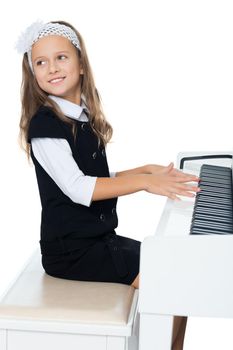 Beautiful little girl in the music school, learning to play the piano . the girl looked away from the piano - Isolated on white background