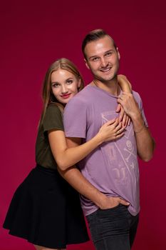 Young nice couple posing in the studio, express emotions and gestures, smiling, on a burgundy background with copy space for your advertisement or written text.