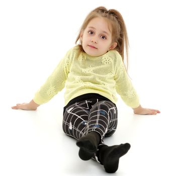 Beautiful little girl is sitting on the floor in the studio. The concept of a happy childhood, beauty and fashion. Isolated on white background.