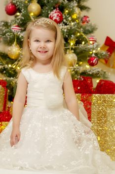 Beautiful little girl near the Christmas tree. The concept of family holidays, children's emotions.