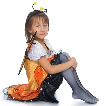 Cute little girl in the butterfly costume . Girl sitting on the floor turned sideways to the camera - Isolated on white background