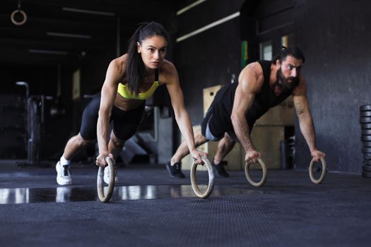 Sporty man and woman doing push-ups on rings