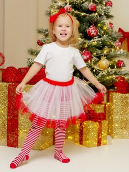 Beautiful little girl near the Christmas tree. The concept of family holidays, children's emotions.