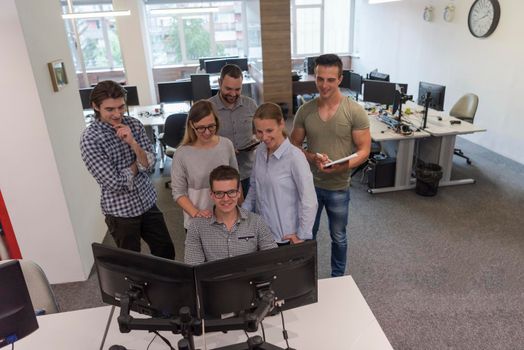 group of young startup business people standing as team at office desk while working on everyday job