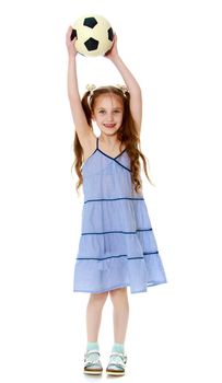 Joyful little girl with long pigtails to her waist and braided white bows. In a long blue dress. Holding up a soccer ball - Isolated on white background