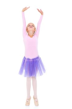 Cute little girl dreams of becoming a ballerina. The girl in the tutu is dancing in the room while she is studying ballet. Isolated on white background.