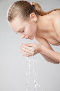Closeup portrait of a beautiful woman washing her clean face with water
