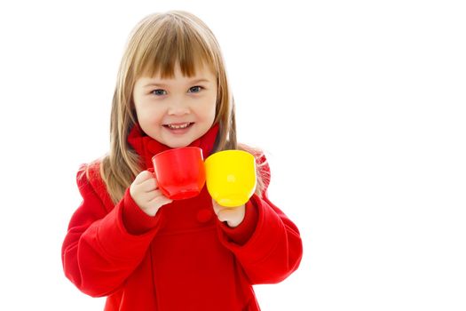 A cute little girl holding mugs in her hands. A healthy diet concept. Isolated on white background.