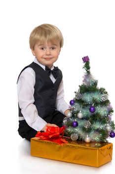 Cute little boy in white shirt, waistcoat and tie ,sitting around the Christmas tree - Isolated on white background