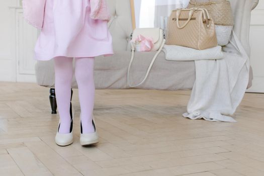 Little child playing with mommy high heels shoes in the interior