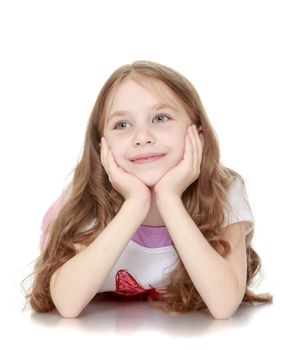 Beautiful little girl with long brown hair to her waist . Girl lying on the floor with his head in his hands , and looking in the direction - Isolated on white background