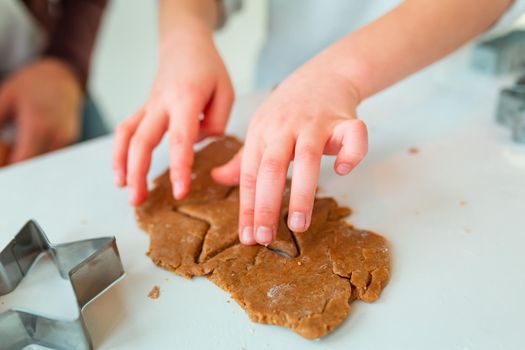 Kid's hands making gingerbread, cutting cookies of gingerbread dough. Christmas bakery. Friends making gingerbread view from above. Festive food, cooking process, family culinary, Christmas and New Year traditions concept