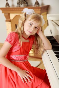 Dreaming little girl in a long orange dress,with long blonde hair braided in pigtails . Close-up