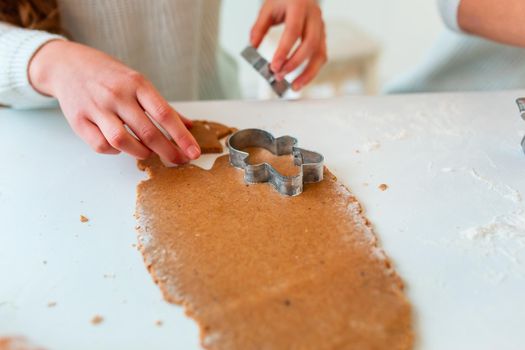 Kid's hands making gingerbread, cutting cookies of gingerbread dough. Christmas bakery. Friends making gingerbread view from above. Festive food, cooking process, family culinary, Christmas and New Year traditions concept