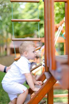 Little caucasian male baby playing on children playground. Concept of childhood and summer.