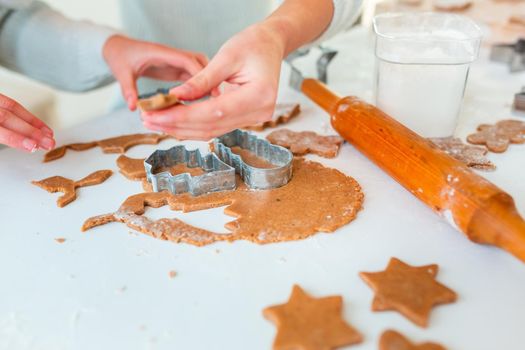 Kid's hands making gingerbread, cutting cookies of gingerbread dough. Christmas bakery. Friends making gingerbread view from above. Festive food, cooking process, family culinary, Christmas and New Year traditions concept