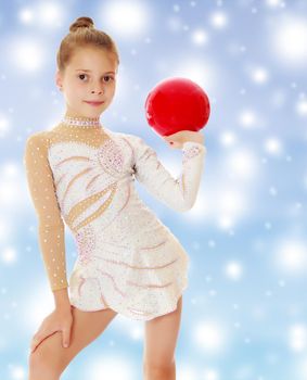 Beautiful little girl gymnast in elegant dress, posing with a red ball.On a blue background with large, white, Christmas or new year's snowflakes.