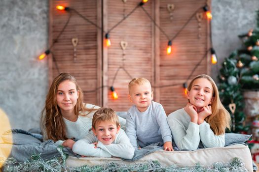 Happy kids siblings having fun on the bed near the Christmas tree on Christmas morning. Christmas family morning, christmas mood concept